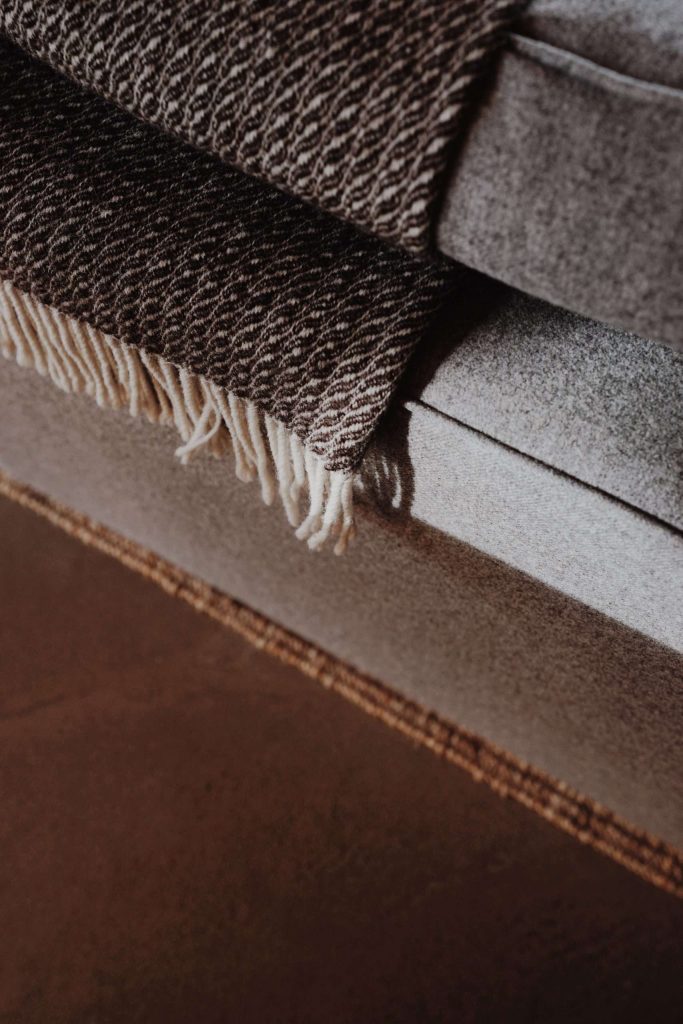 A closeup of the sofa, highlighting the stylish Skye Weavers throws which adorn The Black Shed self-catering accomodation.