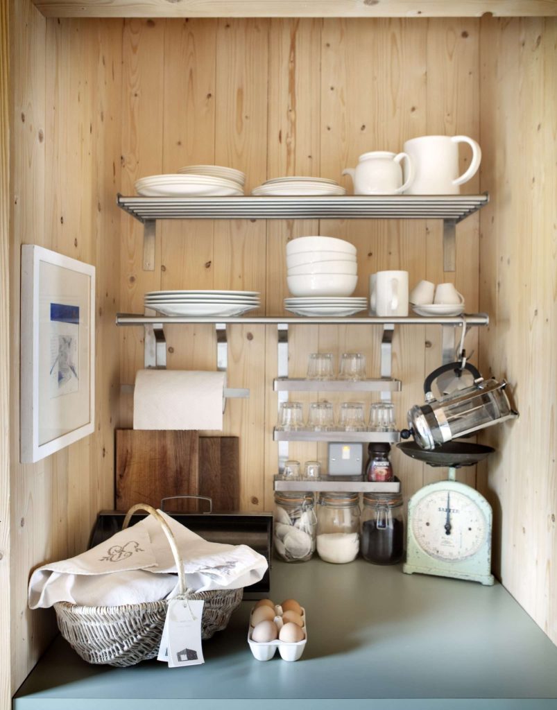 A closeup view of the kitchen pantry, highlighting the kitchen utensils and dinnerware, as well as the welcome basket of fresh, local & home-made foods. 